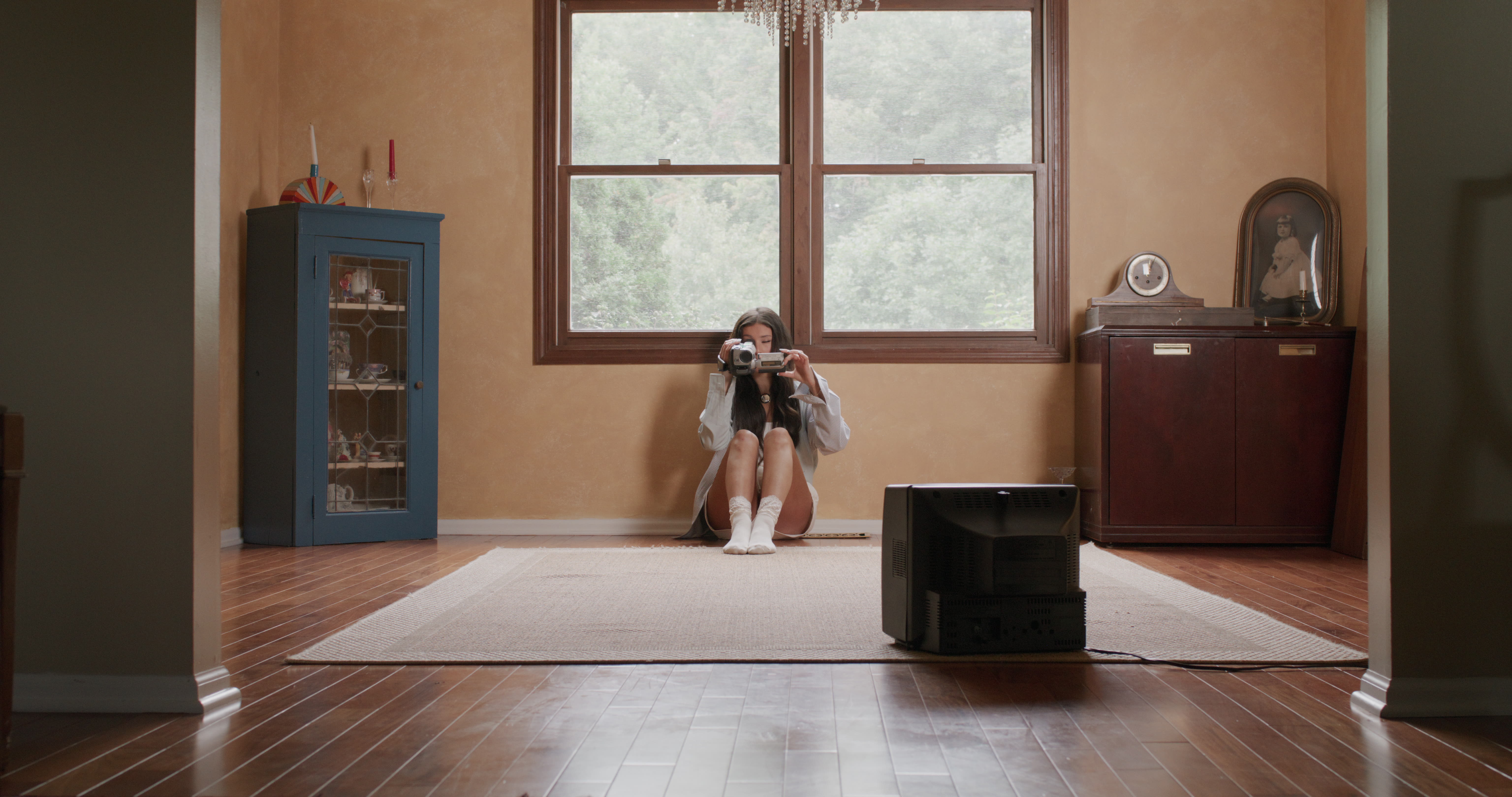 From the Cleveland music video: maryjo sits on the floor of a living room holding a camcorder.